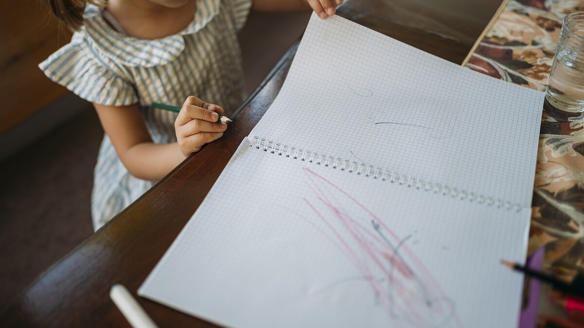 Enfant qui dessine une maison facile au crayon sur un cahier