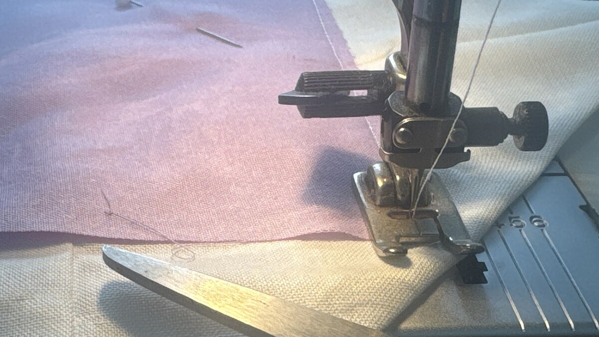 Machine à coudre piquant un tissu rose pour illustrer des idées à coudre faciles