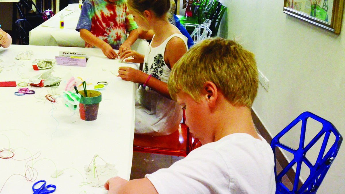Élèves réalisant une activité manuelle avec papier et ficelle en classe