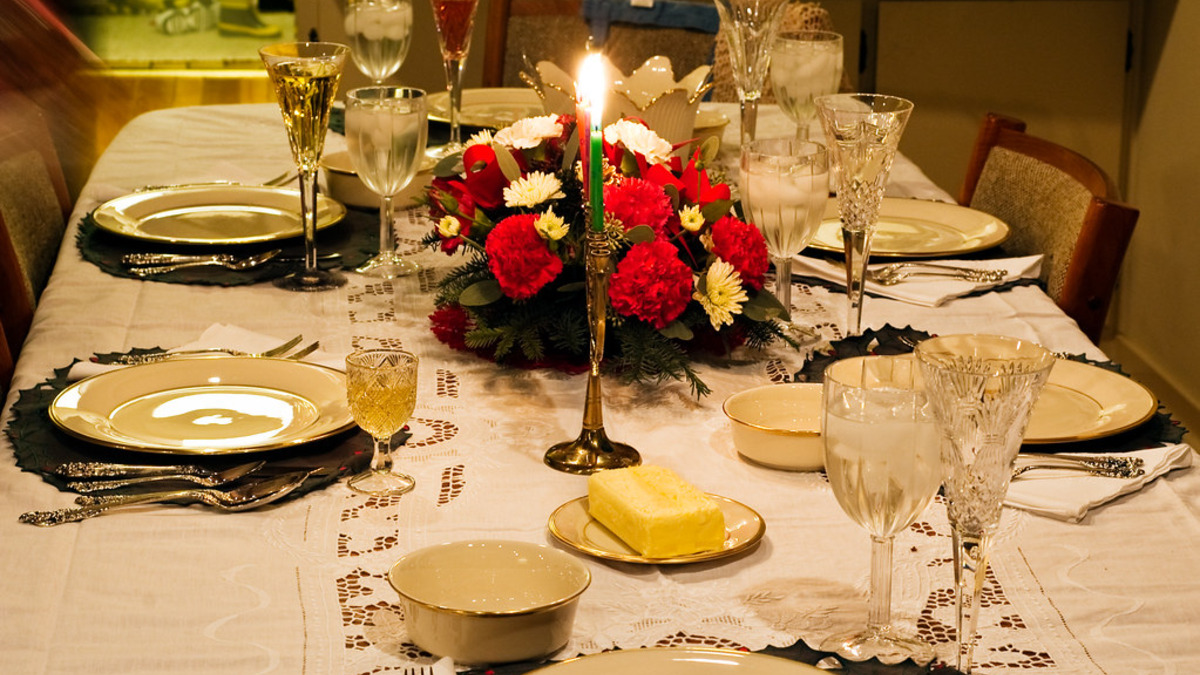 Table de fête de Noël avec nappe blanche, vaisselle et fleurs rouges