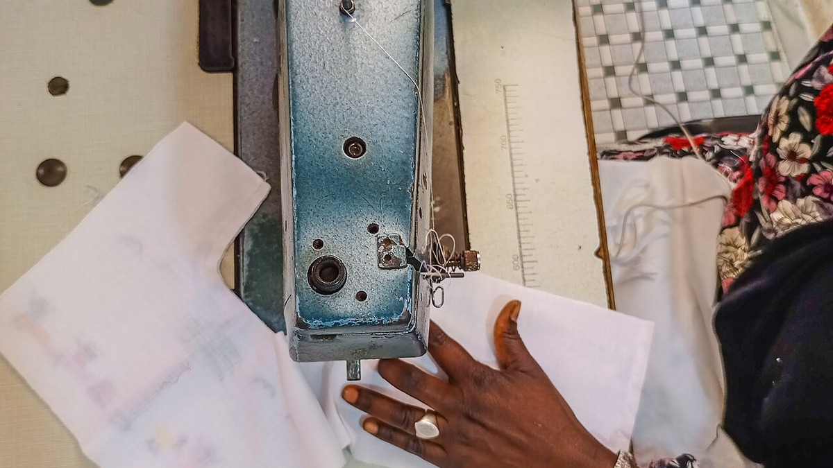 Mains en train de coudre du tissu à la machine dans un atelier