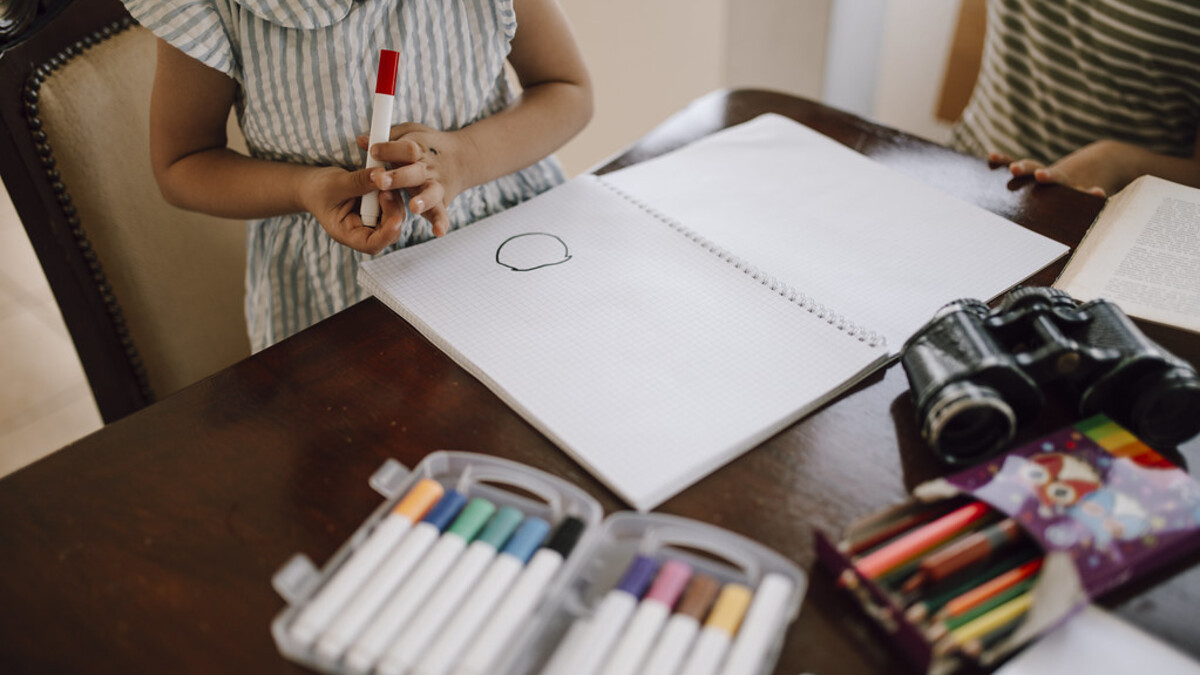 Enfant dessinant à une table avec des feutres pour une activité manuelle facile
