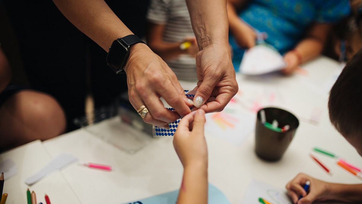 Enfants et adulte réalisant une activité manuelle autour d’une table
