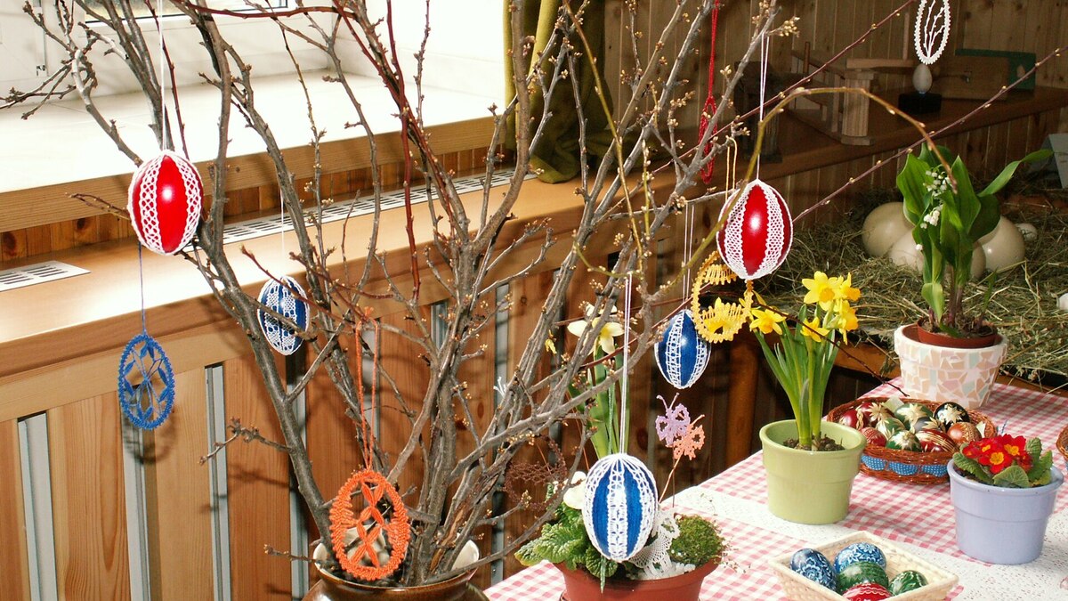 Œufs décoratifs de Pâques habillés de crochet suspendus à des branches